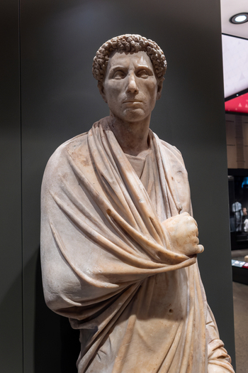 Giza Egypt 16 May 2026 View of an ancient marble statue of a man wearing a toga at the Grand Egyptian Museum showcasing intricate drapery and classical features.