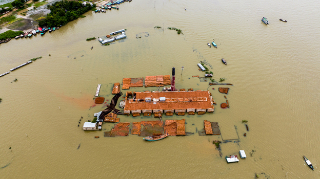 Aerial view of the Baish Mowza Sarak Bazar brick kiln partially submerged in floodwaters with small boats navigating the surrounding area in Nabinagar Chittagong Division Bangladesh. Aerial view of the Baish Mowza Sarak Bazar brick kiln partially submerged in floodwaters with small boats navigating the surrounding area in Nabinagar Chittagong Division Bangladesh.