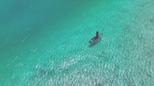 Aerial view of a person paddleboarding in turquoise water Maldives. Aerial view of a person paddleboarding in turquoise water Maldives.