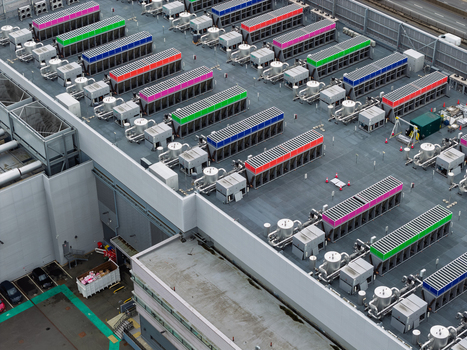 Aerial view of a data center rooftop featuring rows of colorful cooling units industrial ventilation systems and pipes in the United Kingdom.