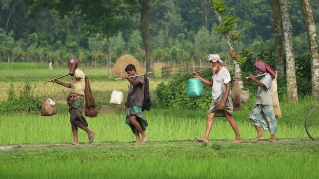 View of fishermen walking with nets through fields Bangladesh.