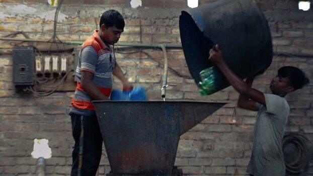View of workers pouring plastic bottles into a machine Bangladesh. View of workers pouring plastic bottles into a machine Bangladesh.