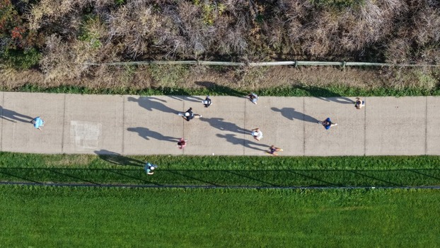 Aerial view of people walking along a paved path in a park with green grass and trees in Boulder Colorado United States. Aerial view of people walking along a paved path in a park with green grass and trees in Boulder Colorado United States.