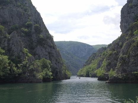 View of Matka Canyon with steep rocky cliffs lush green vegetation and a small boat on the river in Matka Grad Skopje North Macedonia.