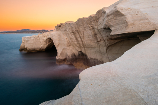 View of Sarakiniko Beach with its unique white volcanic rock formations and sea caves at sunset in Milos Greece. View of Sarakiniko Beach with its unique white volcanic rock formations and sea caves at sunset in Milos Greece.