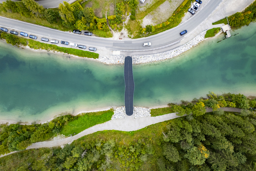 Aerial view of a bridge crossing a vibrant turquoise river bordered by lush greenery and a winding road Plansee Tyrol Austria. Aerial view of a bridge crossing a vibrant turquoise river bordered by lush greenery and a winding road Plansee Tyrol Austria.