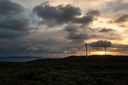 View of wind turbines at the Sandpatch wind farm silhouetted against a dramatic sunset sky with dark coastal vegetation and the ocean in Sandpatch Western Australia Australia. View of wind turbines at the Sandpatch wind farm silhouetted against a dramatic sunset sky with dark coastal vegetation and the ocean in Sandpatch Western Australia Australia.