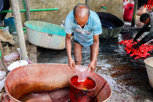 Narayanganj Bangladesh 29 March 2026 View of a man in a vibrant scene dyeing fabric in colorful tubs the scene bathed in warm sunlight creating a striking contrast of textures and tones. Narayanganj Bangladesh 29 March 2026 View of a man in a vibrant scene dyeing fabric in colorful tubs the scene bathed in warm sunlight creating a striking contrast of textures and tones.