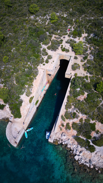 Aerial view of the Yugoslav army underground boat shelter Potkop Parja with turquoise water and lush green vegetation in Rogacic Splitsko dalmatinska Croatia. Aerial view of the Yugoslav army underground boat shelter Potkop Parja with turquoise water and lush green vegetation in Rogacic Splitsko dalmatinska Croatia.