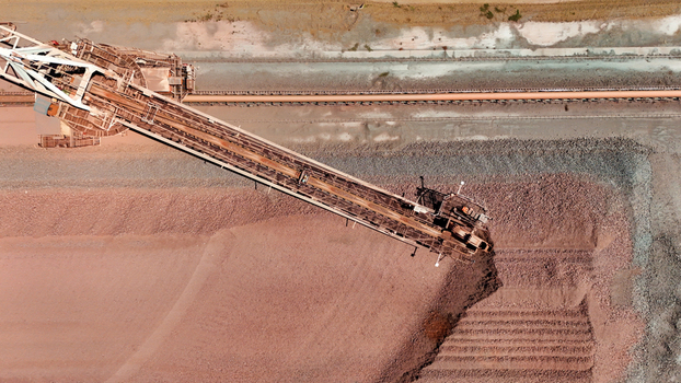 Aerial view of industrial stacker building vast reddish brown ore pile showcasing stark textured earth Rustenburg North West South Africa. Aerial view of industrial stacker building vast reddish brown ore pile showcasing stark textured earth Rustenburg North West South Africa.
