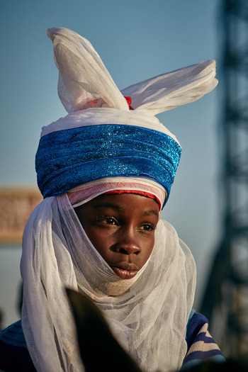 Zaria City Nigeria 22 March 2026 View of a young person adorned in a vibrant blue and white turban their serene expression framed by soft flowing fabrics under a clear sky. Zaria City Nigeria 22 March 2026 View of a young person adorned in a vibrant blue and white turban their serene expression framed by soft flowing fabrics under a clear sky.