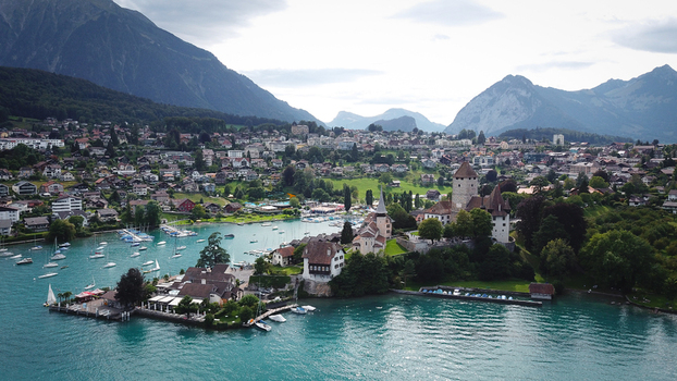 Aerial view of Schloss Spiez overlooking Lake Thun with sailboats historic architecture and the Swiss Alps under a cloudy sky Spiez Bern Switzerland. Aerial view of Schloss Spiez overlooking Lake Thun with sailboats historic architecture and the Swiss Alps under a cloudy sky Spiez Bern Switzerland.