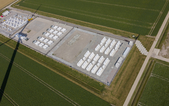 Aerial view of the Battery Energy Storage System at Wind Park with rows of white storage containers set amidst green agricultural fields in Dronten Flevoland Netherlands. Aerial view of the Battery Energy Storage System at Wind Park with rows of white storage containers set amidst green agricultural fields in Dronten Flevoland Netherlands.