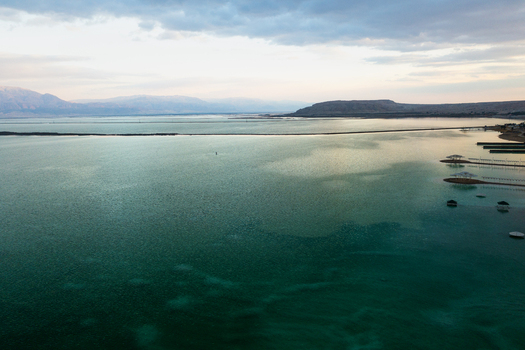 Aerial view of the Dead Sea s turquoise waters meet the rugged shoreline under a muted sky Ein Bokek South District Israel. Aerial view of the Dead Sea s turquoise waters meet the rugged shoreline under a muted sky Ein Bokek South District Israel.