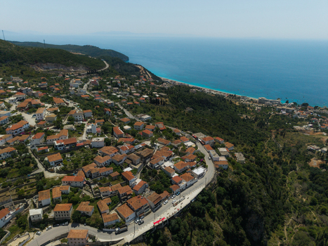 Aerial view of traditional stone houses with red tiled roofs on a green hillside overlooking the turquoise sea Dhermi Vlore County Albania. Aerial view of traditional stone houses with red tiled roofs on a green hillside overlooking the turquoise sea Dhermi Vlore County Albania.