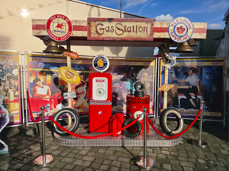 Hanover Lower Saxony Germany 06 April 2026 View of a vintage themed gas station display featuring a red fuel pump retro advertising signs and classic car tires on a paved surface.