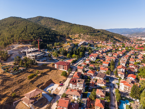 Aerial view of the town of Velingrad nestled among green hills with residential buildings construction sites and a clear blue sky in Velingrad Pazardzhik Bulgaria. Aerial view of the town of Velingrad nestled among green hills with residential buildings construction sites and a clear blue sky in Velingrad Pazardzhik Bulgaria.