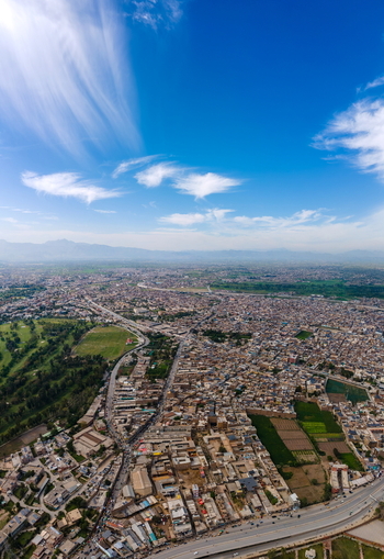 Aerial view of Bala Hisar Fort surrounded by the dense urban landscape featuring historic fortifications and sprawling rooftops in Peshawar Khyber Pakhtunkhwa Pakistan.
