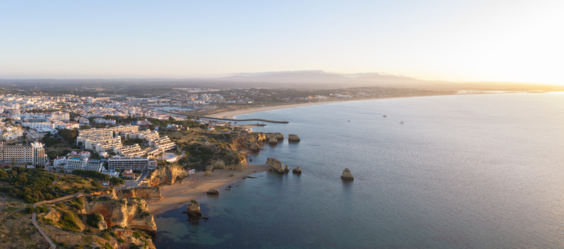 Aerial view of the coastline of Lagos with sandy beaches rocky cliffs and the town buildings along the Atlantic Ocean in Lagos Faro District Portugal.