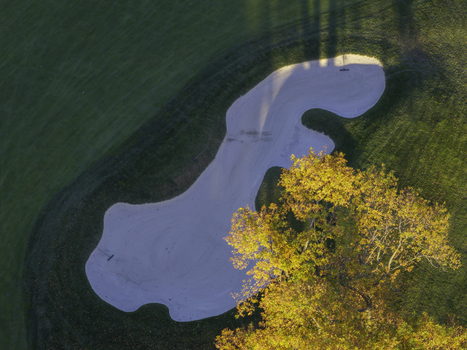 Aerial view of a sand trap on a golf course in autumn with vibrant yellow foliage on a nearby tree and green grass in Glenview Illinois United States. Aerial view of a sand trap on a golf course in autumn with vibrant yellow foliage on a nearby tree and green grass in Glenview Illinois United States.