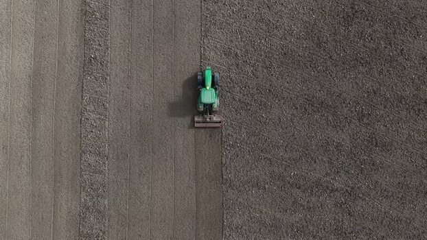 Aerial view of a green tractor plowing a dark brown field Portugal. Aerial view of a green tractor plowing a dark brown field Portugal.