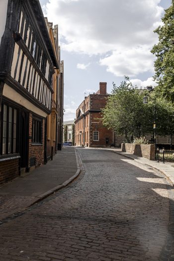 View of a historic cobblestone street lined with timber framed buildings and red brick architecture in Coventry England United Kingdom.