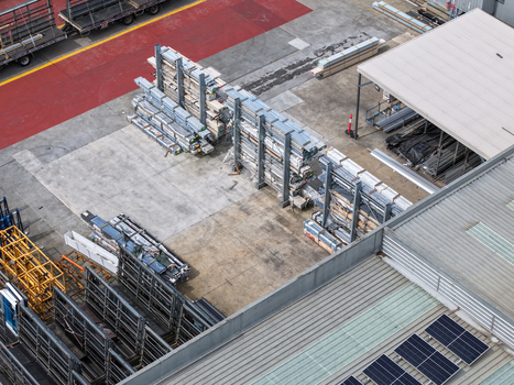 Aerial view of industrial site with metal storage racks construction materials and solar panels on a warehouse roof in Melbourne VIC Australia.
