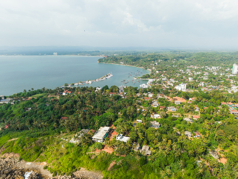 Aerial view of Secret Beach Mirissa featuring lush tropical vegetation coastal buildings and the turquoise Indian Ocean under a bright sky in Mirissa Southern Province Sri Lanka. Aerial view of Secret Beach Mirissa featuring lush tropical vegetation coastal buildings and the turquoise Indian Ocean under a bright sky in Mirissa Southern Province Sri Lanka.