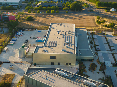Aerial view of the Moderna Innovation and Technology Centre featuring a modern building with solar panels adjacent parking and surrounding landscape in Harwell Oxford England United Kingdom.