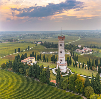 Aerial view of the Tower of San Martino della Battaglia standing amidst lush vineyards and cypress trees under a soft sunset sky in San Martino della Battaglia Lombardia Italy. Aerial view of the Tower of San Martino della Battaglia standing amidst lush vineyards and cypress trees under a soft sunset sky in San Martino della Battaglia Lombardia Italy.