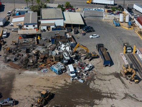 Aerial view of a scrap metal recycling facility with piles of discarded vehicles heavy machinery and industrial equipment in Carson California United States.