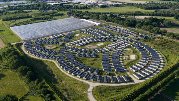 Aerial view of a holiday park with rows of mobile homes arranged in a circular pattern surrounded by green fields trees and a large greenhouse in Venlo Limburg Netherlands. Aerial view of a holiday park with rows of mobile homes arranged in a circular pattern surrounded by green fields trees and a large greenhouse in Venlo Limburg Netherlands.