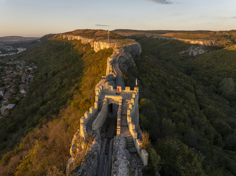 Aerial view of Fortress Ovech with its stone walls and wooden walkway atop a cliff surrounded by lush forest at sunset in Provadia Varna Bulgaria. Aerial view of Fortress Ovech with its stone walls and wooden walkway atop a cliff surrounded by lush forest at sunset in Provadia Varna Bulgaria.