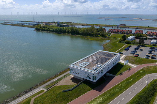 Kornwerderzand Netherlands 14 May 2026 Aerial view of the Afsluitdijk Wadden Center building with its hexagonal facade overlooking the water and a distant offshore wind farm. Kornwerderzand Netherlands 14 May 2026 Aerial view of the Afsluitdijk Wadden Center building with its hexagonal facade overlooking the water and a distant offshore wind farm.