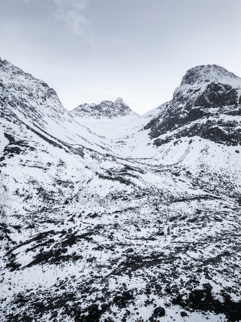 Aerial view of the snow covered peaks and rugged valley of Grotfjord under an overcast winter sky in Tromvik Troms Norway. Aerial view of the snow covered peaks and rugged valley of Grotfjord under an overcast winter sky in Tromvik Troms Norway.