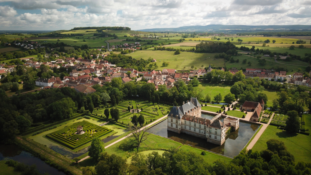 Aerial view of Chateau de Cormatin with its moat formal gardens and labyrinth surrounded by the village and lush countryside Cormatin Bourgogne Franche Comte France. Aerial view of Chateau de Cormatin with its moat formal gardens and labyrinth surrounded by the village and lush countryside Cormatin Bourgogne Franche Comte France.