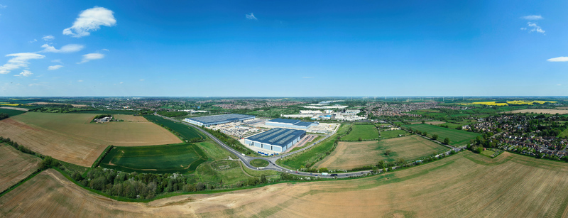 Aerial view of Symmetry Park featuring large modern warehouses surrounded by vast agricultural fields and a road network under a clear blue sky in Kettering England United Kingdom. Aerial view of Symmetry Park featuring large modern warehouses surrounded by vast agricultural fields and a road network under a clear blue sky in Kettering England United Kingdom.