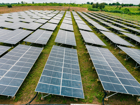Aerial view of a large solar farm with rows of photovoltaic panels installed on green grassy fields in Ogun State Nigeria.