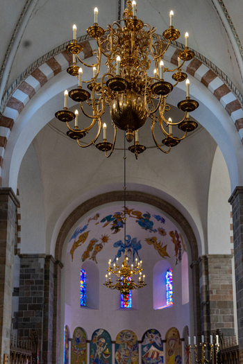 View of the ornate brass chandeliers and colorful frescoes inside the historic Ribe Cathedral with vaulted arches Ribe Denmark. View of the ornate brass chandeliers and colorful frescoes inside the historic Ribe Cathedral with vaulted arches Ribe Denmark.