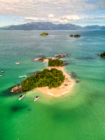 Aerial view of Ilha Cataguas with lush vegetation a sandy beach and turquoise waters surrounded by boats in Rio de Janeiro Brazil. Aerial view of Ilha Cataguas with lush vegetation a sandy beach and turquoise waters surrounded by boats in Rio de Janeiro Brazil.