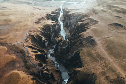 Aerial view of the serpentine river carves a deep gorge through the rugged landscape its waters reflecting the pale sky above Fjadrargljufur Iceland. Aerial view of the serpentine river carves a deep gorge through the rugged landscape its waters reflecting the pale sky above Fjadrargljufur Iceland.