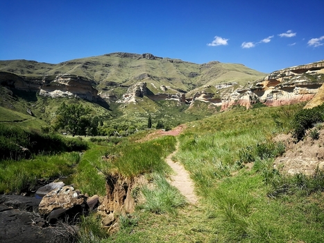View of the dramatic sandstone cliffs and lush green valley along a hiking trail in Golden Gate Highlands National Park in Clarens Free State South Africa. View of the dramatic sandstone cliffs and lush green valley along a hiking trail in Golden Gate Highlands National Park in Clarens Free State South Africa.
