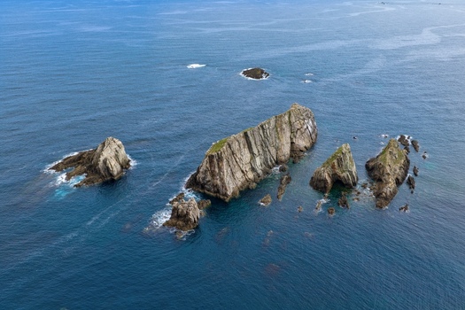 Aerial view of the jagged rock formations and islets of Silence Beach surrounded by the deep blue waters of the Cantabrian Sea in Cudillero Asturias Spain.