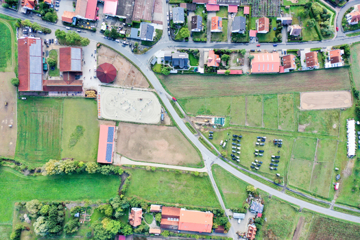 Aerial view of Reitclub In der Point Poxdorf with its riding arena stables and surrounding residential houses in Poxdorf Bayern Germany. Aerial view of Reitclub In der Point Poxdorf with its riding arena stables and surrounding residential houses in Poxdorf Bayern Germany.