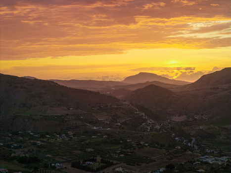 Aerial view of the rolling hills of Sicily at sunset with warm golden light illuminating the landscape scattered houses and distant mountains near Palermo Sicily Italy. Aerial view of the rolling hills of Sicily at sunset with warm golden light illuminating the landscape scattered houses and distant mountains near Palermo Sicily Italy.