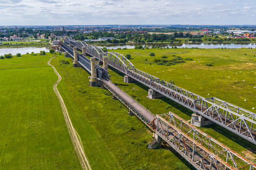 Aerial view of the historic Tczew Bridges spanning the Vistula River with stone towers and steel truss structures surrounded by green meadows in Tczew Pomeranian Voivodeship Poland. Aerial view of the historic Tczew Bridges spanning the Vistula River with stone towers and steel truss structures surrounded by green meadows in Tczew Pomeranian Voivodeship Poland.