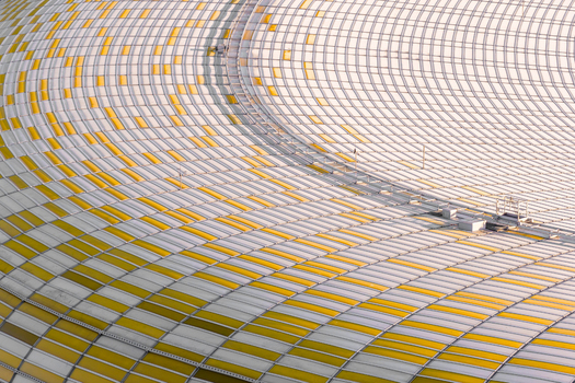 Aerial view of the Polsat Plus Arena its sweeping curves adorned with a mosaic of gold and white panels under the soft light Gdansk Pomeranian Voivodeship Poland. Aerial view of the Polsat Plus Arena its sweeping curves adorned with a mosaic of gold and white panels under the soft light Gdansk Pomeranian Voivodeship Poland.