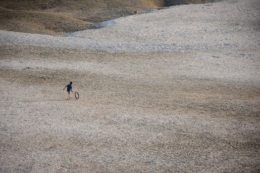 Kushtia District Bangladesh 10 March 2020 View of a young boy playing with a tire on a vast sandy landscape under soft daylight. Kushtia District Bangladesh 10 March 2020 View of a young boy playing with a tire on a vast sandy landscape under soft daylight.