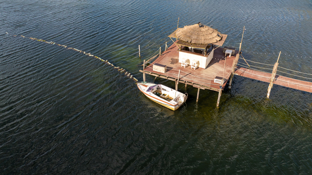 Aerial view of a traditional thatched roof hut on stilts with a small boat moored alongside at Salinas de Aveiro Aveiro Portugal. Aerial view of a traditional thatched roof hut on stilts with a small boat moored alongside at Salinas de Aveiro Aveiro Portugal.