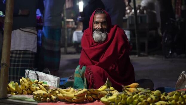 View of an elderly man in a red shawl selling bananas Bangladesh. View of an elderly man in a red shawl selling bananas Bangladesh.